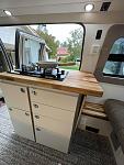 New Galley replacing door mounted storage box and moved dual burner stove from driver side to passenger side of van.